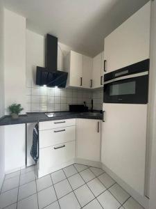 a kitchen with white cabinets and a black appliance at Modernes Apartment in Chemnitz in Chemnitz