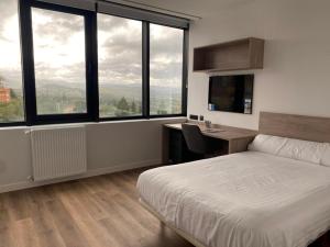 Schlafzimmer mit einem Bett, einem Schreibtisch und Fenstern in der Unterkunft Residencia Universitaria Micampus Oviedo La Gruta in Oviedo