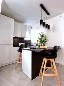 a kitchen with a black and white counter and stools at Palais 5min Luxury&Cinema Studio in Cannes