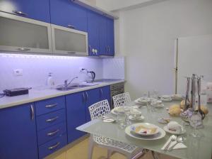 una cucina con armadi blu, tavolo e sedie di COASTAL RETREAT - Beach Apartment Vlore a Vlorë