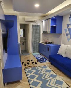 Sala de estar azul con sofá azul y cocina en Apartment Kalibata City by PanBul en Yakarta