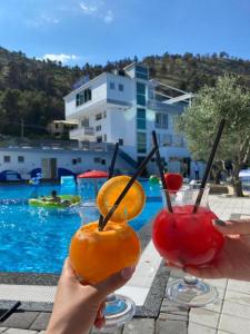 una persona sosteniendo dos cócteles frente a una piscina en PRINCIPE DEL LAGO, en Shkodër