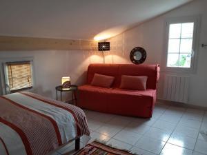 Saint-Pierre-de-VassolsにあるMaison du Manescauのリビングルーム(赤いソファ、ベッド付)