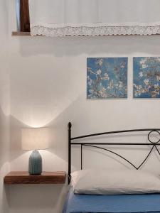 1 dormitorio con 1 cama con lámpara y pinturas en Tanca Noa en Tortolì