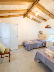 una camera con due letti in una stanza con soffitti in legno di Tanca Noa a Tortolì