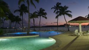 una piscina por la noche con palmeras y sillas en En bord de plage Baie Nettlé, appart 4 couchages tout rénové en Saint Martin