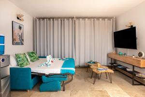 ein Wohnzimmer mit einem blauen Sofa und einem TV in der Unterkunft En bord de plage Baie Nettlé, appart 4 couchages tout rénové in Saint Martin