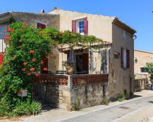 an old house with a balcony with red flowers at Maison du Manescau in Saint-Pierre-de-Vassols