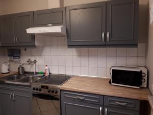 a kitchen with black cabinets and a sink and a microwave at Bursztynowa Wyspa in Gdańsk