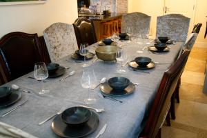een lange tafel met borden en wijnglazen erop bij Ultra Deluxe Versace Villa Hot Tub Cinema Room in Saffron Walden