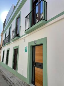 a white building with a wooden door and two balconies at Apartamentos BRAVO MURILLO con garaje en centro histórico in Badajoz