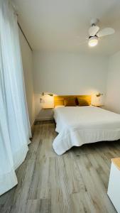 um quarto com uma grande cama branca e pisos em madeira em Apartamentos BRAVO MURILLO con garaje en centro histórico em Badajós