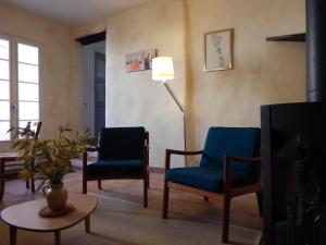 Saint-Pierre-de-VassolsにあるMaison du Manescauのリビングルーム(青い椅子2脚、ランプ付)