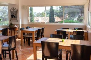 a restaurant with wooden tables and chairs and a window at Hôtel Les Calanques in Les Issambres