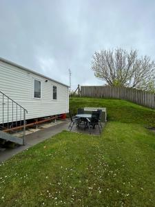 a trailer with a table and chairs in a yard at Delightful 2 bedroom Caravan, Pencnwc, New Quay in Cross Inn
