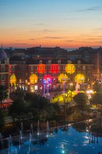 a view of a city at night with a fountain at Novotel Nice Arenas Aeroport in Nice