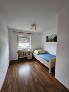 a small bedroom with a blue bed and a window at Stadthostel in Töging am Inn