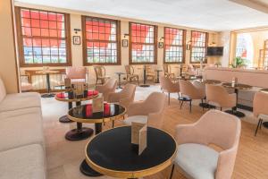 - une salle d'attente avec des tables, des chaises et des fenêtres dans l'établissement L'Hotel De L'Esperance, à Lisieux