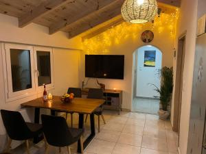 une salle à manger avec une table, des chaises et une télévision dans l'établissement Lemonia Apartment with yard, à Pitsidia