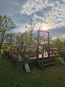 a wooden bench in the grass with the sun in the background at Glamping Livada cu lavanda 