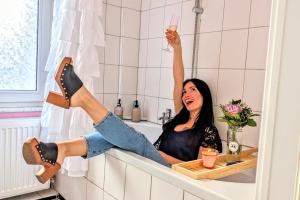 Una mujer sentada en una bañera con la pierna en el baño. en Queen Apartment en Uelzen