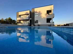 uma casa com piscina em frente a um edifício em Apartmani Kiara em Drage