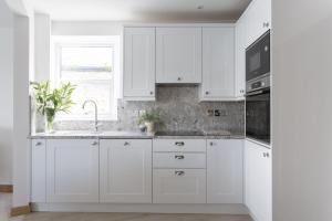 a white kitchen with white cabinets and a window at 28 The Salcombe in Salcombe