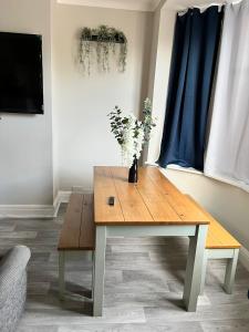 a wooden table with a vase of flowers on it at Kim Family Holiday Get-Away 4 Bedrooms 2 Baths in Blackpool