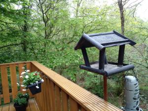 a black bird feeder on a wooden deck at Boshuis Nos Bohio Durbuy in Durbuy