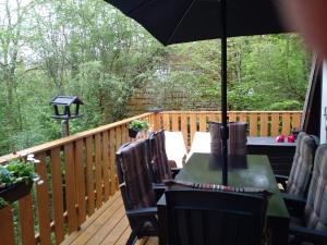 a deck with a table and chairs and an umbrella at Boshuis Nos Bohio Durbuy in Durbuy