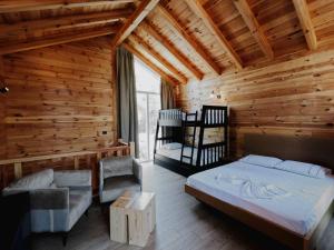una camera da letto con letto e sedie in una camera in legno di Hysaj Agroturizëm a Shkodër