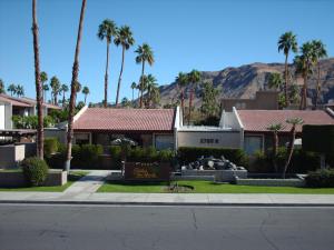 una calle con palmeras y un edificio con un cartel en Casitas del Monte, en Palm Springs