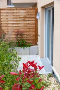 un jardin avec des fleurs rouges devant un bâtiment dans l'établissement Echappée belle Osnyssoise, à Osny