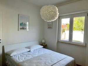 Habitación blanca con cama y lámpara de araña. en Cityside apartment, en Selargius
