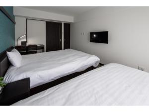 1 dormitorio con 2 camas y TV en la pared en Hotel Thomas Nago - Vacation STAY 40430v, en Nago