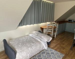 een slaapkamer met een bed, een tafel en een trap bij The Swish - New Forest Get Away in Redlynch