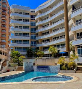 a swimming pool in front of a large apartment building at Apartamento a la orilla de la playa en Pampatar, Isla de Margarita in Pampatar