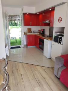 una cocina con armarios rojos y electrodomésticos blancos en 02 - T2 au rdc avec jolie terrasse et porte donnant sur parking comme une maison, en Razac-sur-lʼIsle