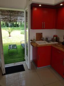 cocina con armarios rojos y vistas a un patio en 02 - T2 au rdc avec jolie terrasse et porte donnant sur parking comme une maison, en Razac-sur-lʼIsle