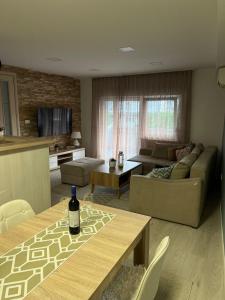 una sala de estar con una mesa con una botella de vino. en Apartman Mak, en Mostar