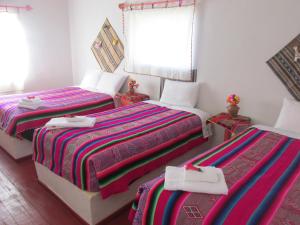 a bedroom with three beds and a window at TITIKAKA NATURAL LODGE - LUQUINA in Chucuito