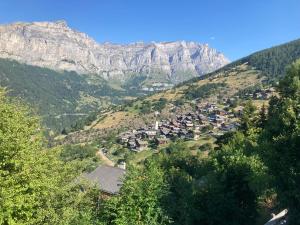 a village on a hill with mountains in the background at Haus Rhodania in Albinen