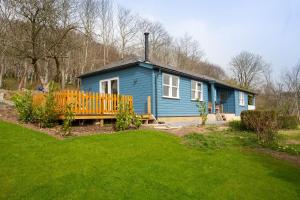 uma casa azul com um banco num quintal em Bowden Wood em Dartmouth