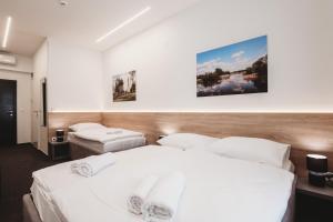 two beds in a hotel room with white sheets at Bells Osijek in Osijek
