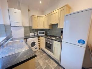 a kitchen with a white refrigerator and a dishwasher at The First Rho in Bishop Auckland