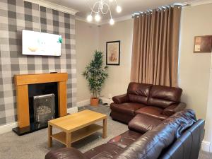 a living room with a leather couch and a fireplace at The First Rho in Bishop Auckland
