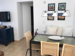 a dining room with a table with chairs and a tv at Costa Ilios 2 bedroom flat in Ornos