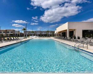 a large swimming pool with chairs and a building at Beautiful 4 suites - Close to Disney 7505 in Orlando