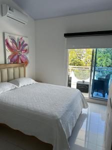 a white bedroom with a bed and a large window at ATLANTIS CASA BOUTIQUE , con jacuzzi cerca de la playa in San Andrés