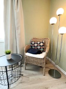Exclusives Apartment in Toplage في فيلهلمسهافن: كرسي الخوص وطاولة في الغرفة